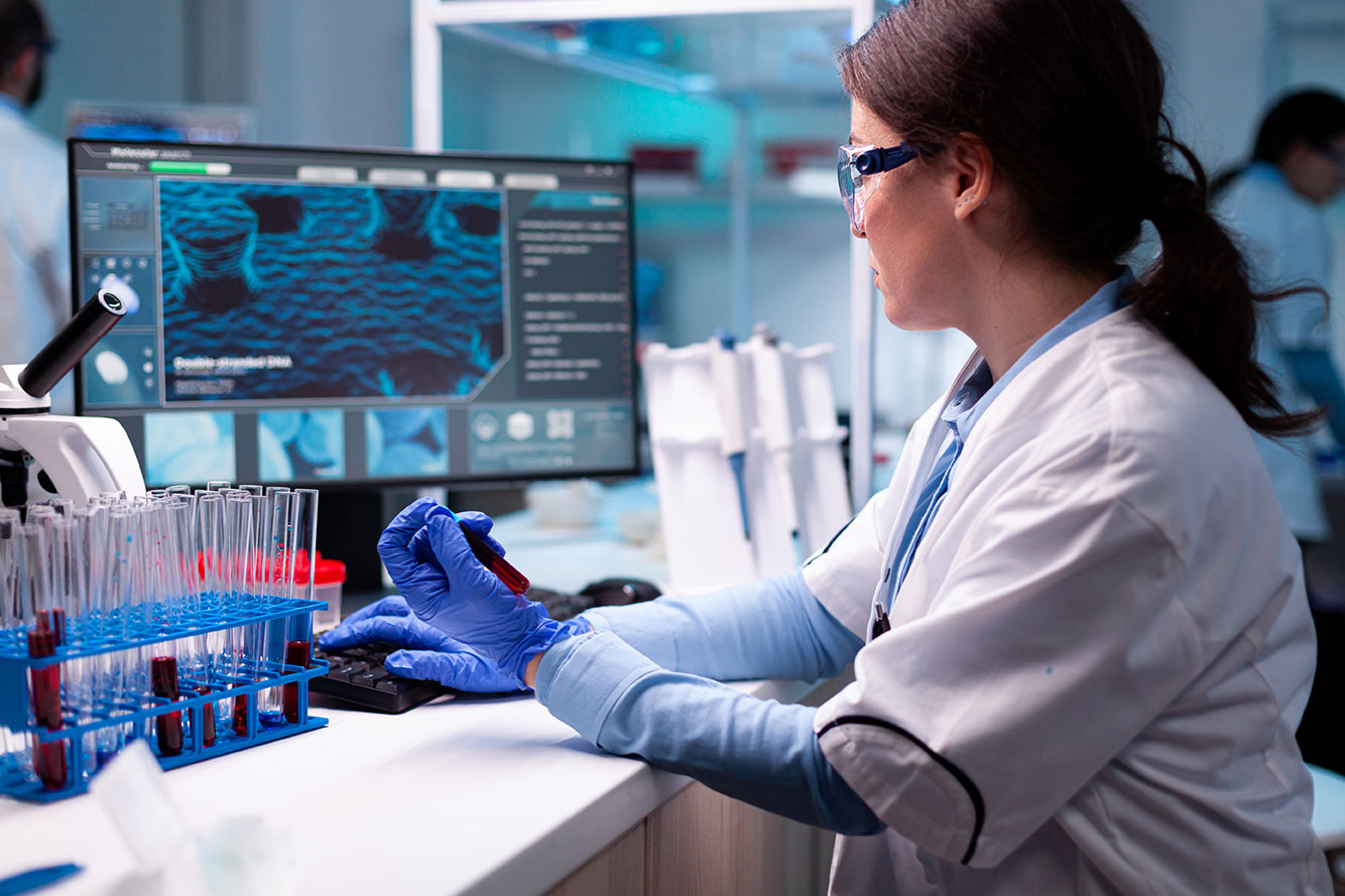 scientist typing laptop holding vacutainer blood healthcare chemistry